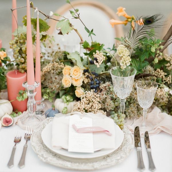 Elegant place setting with a peacock feather, blush candles and garden roses for an Italian wedding celebration